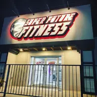 The lit Super Future Fitness sign over the entrance at night